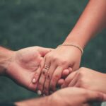 Intimate moment of a couple holding hands, symbolizing love and connection in an outdoor setting.